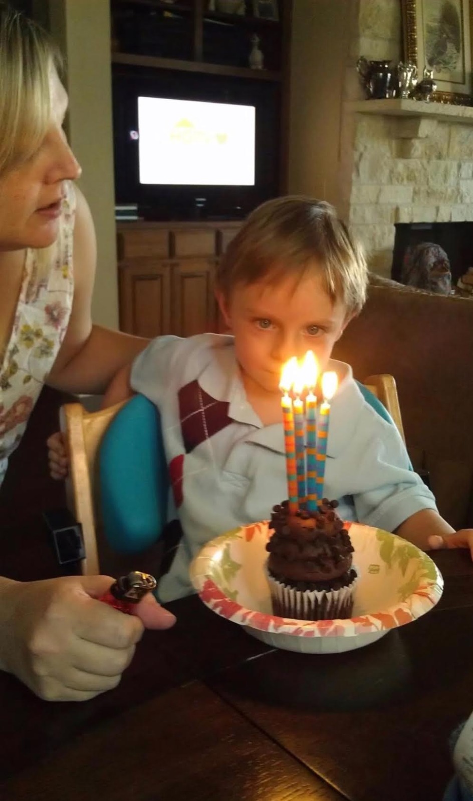 A young boy about to blow out the candles on a birthday cupcake