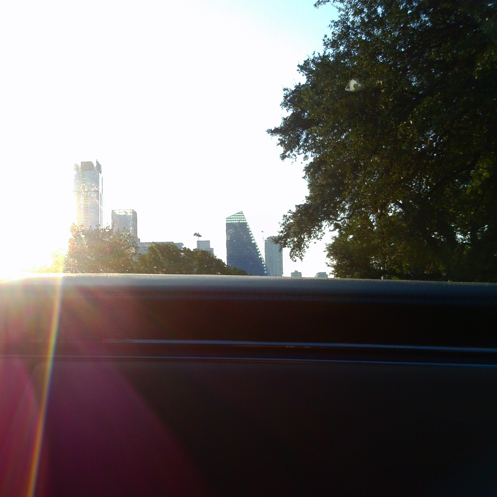The Austin skyline past a car door, with sun flare